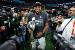 Read more about the article Shirtless Saquon Barkley chugs beers and leads wild Eagles locker room celebrations with $5 billion owner after breaking NFL record in Super Bowl blowout